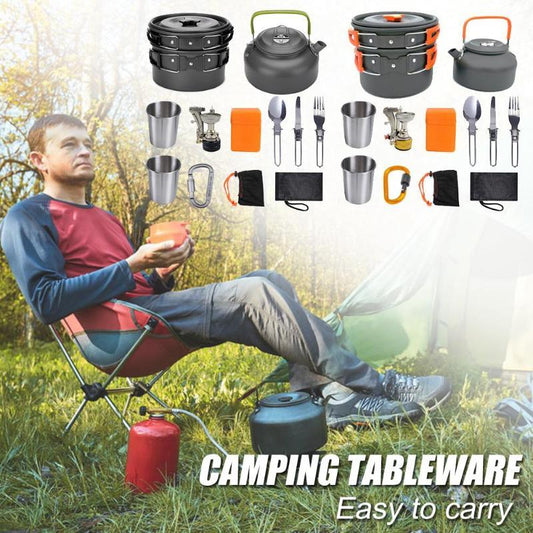 Man sitting outdoors with camping tableware including pots, kettles, and cutlery displayed around him.
