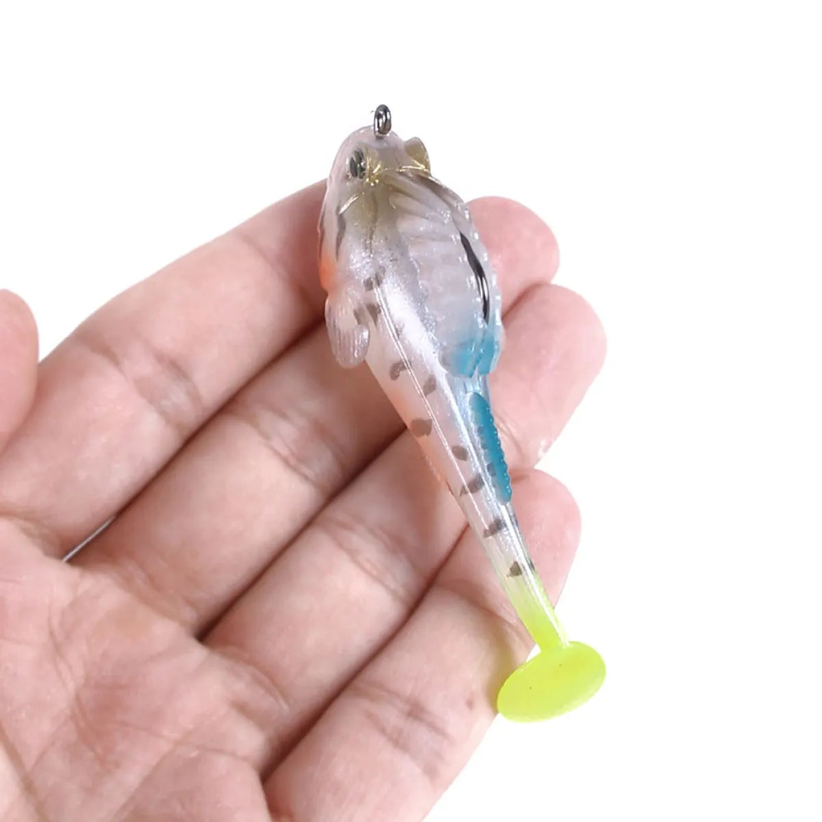 Transparent fishing lure with a yellow tail held in a hand against a white background