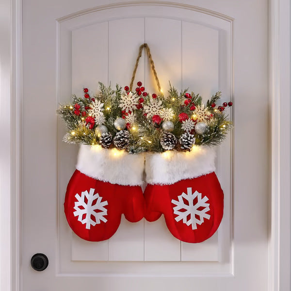 Decorative Christmas stockings with floral arrangement and lights on a white door.