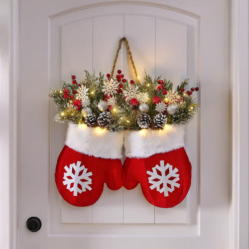 Decorative Christmas stockings with floral arrangement and lights on a white door.