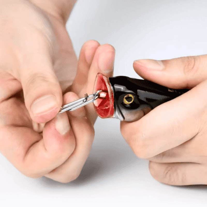 Person using a fishing hook retriever tool on a fish